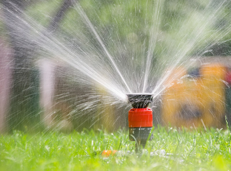 A sprinkler spraying water over a lawn.